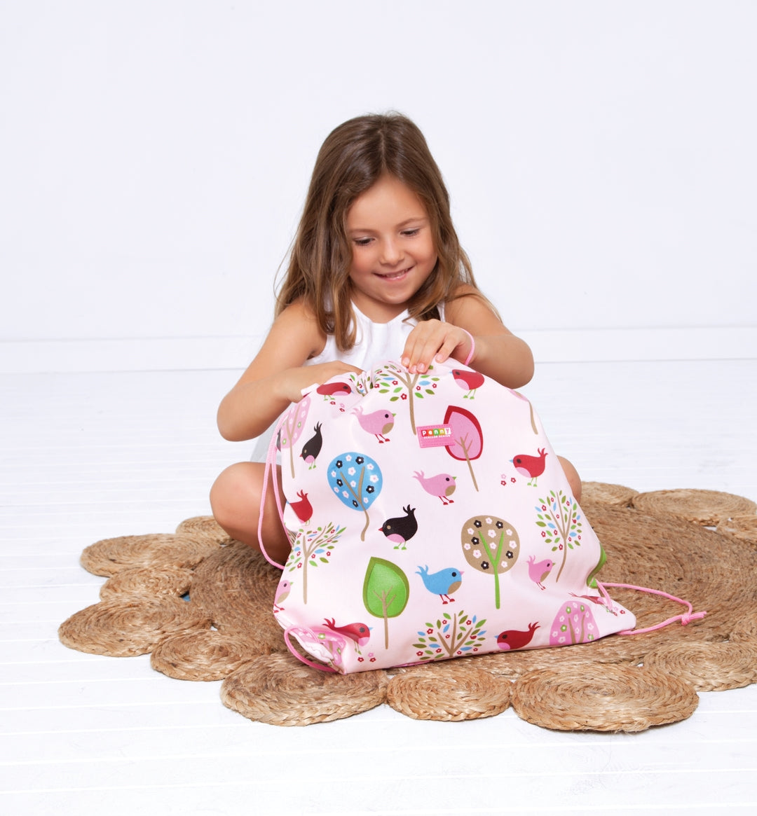Girl sitting on a mat looking inside the Penny Scallan Drawstring Bag Chirpy Bird